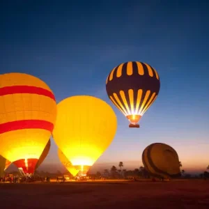 Luxor sunrise hot air balloon ride with colorful balloons flying above the Nile and ancient temples.